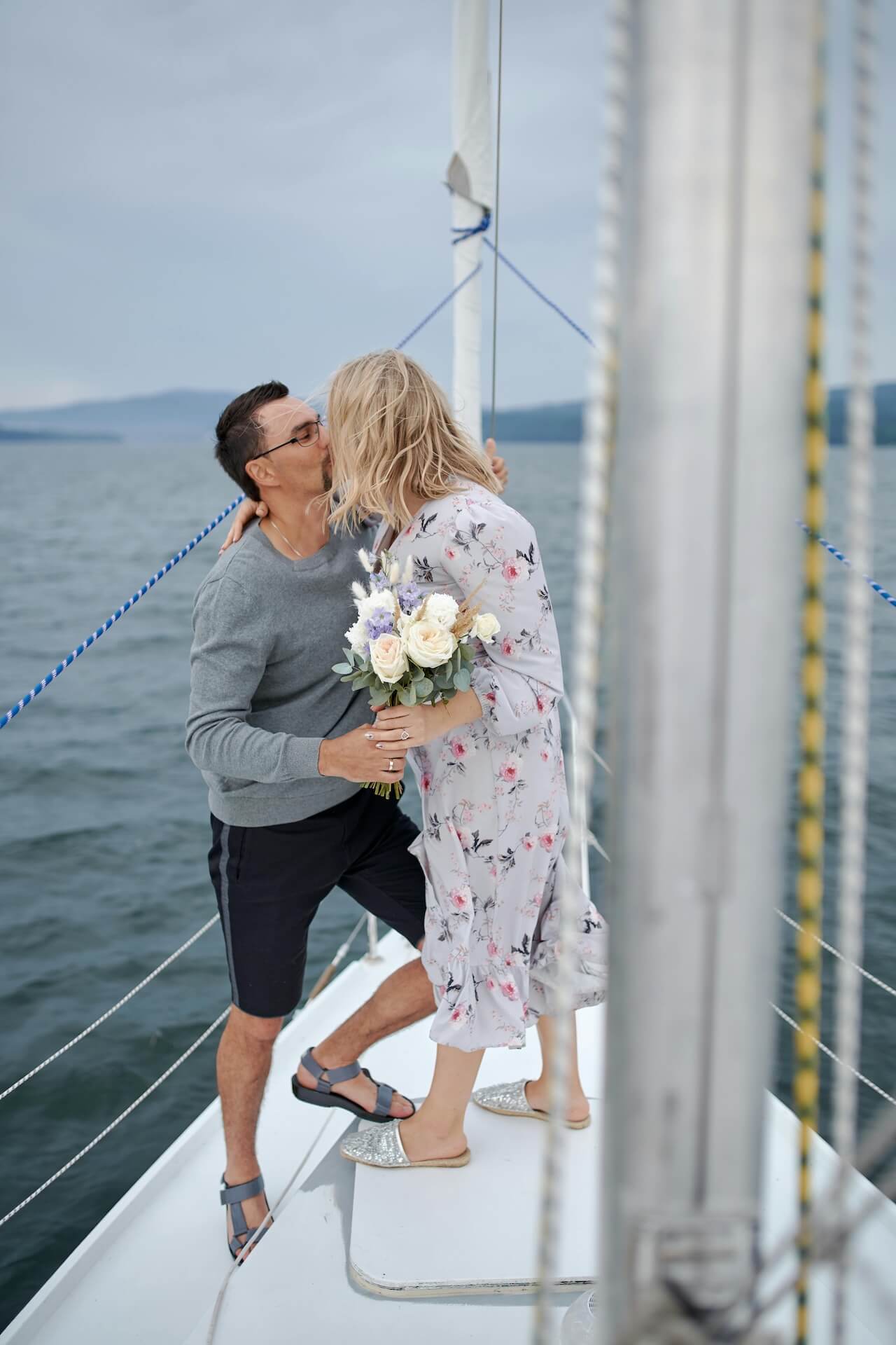 Couple kissing on boat with a flower bouquet